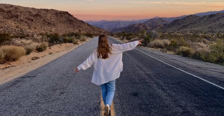 The Placement Process au pair running with stretched out arms down a highway in the desert